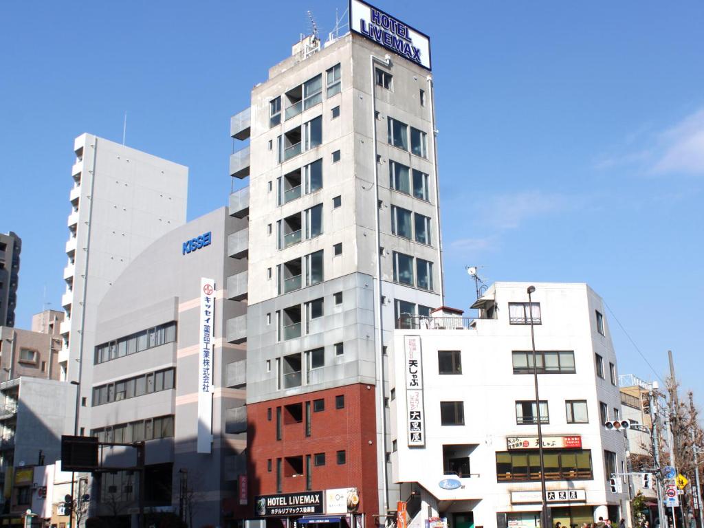 un edificio blanco alto con un cartel encima en HOTEL LiVEMAX BUDGET Korakuen, en Tokio