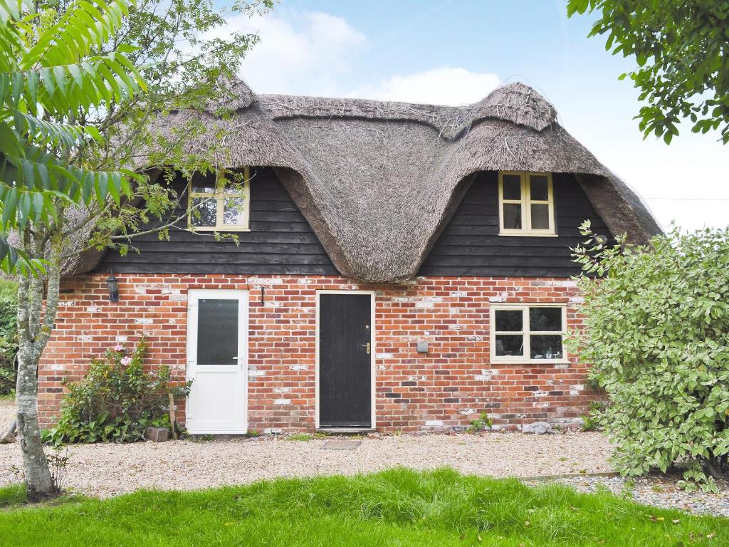 uma casa com telhado de palha e uma porta branca em Walnut Tree Cottage em Fordingbridge