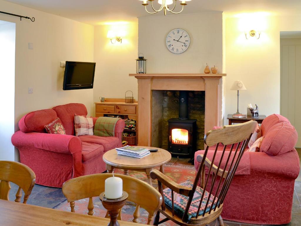 a living room with red furniture and a fireplace at The Steading At Nabny in Dundrennan