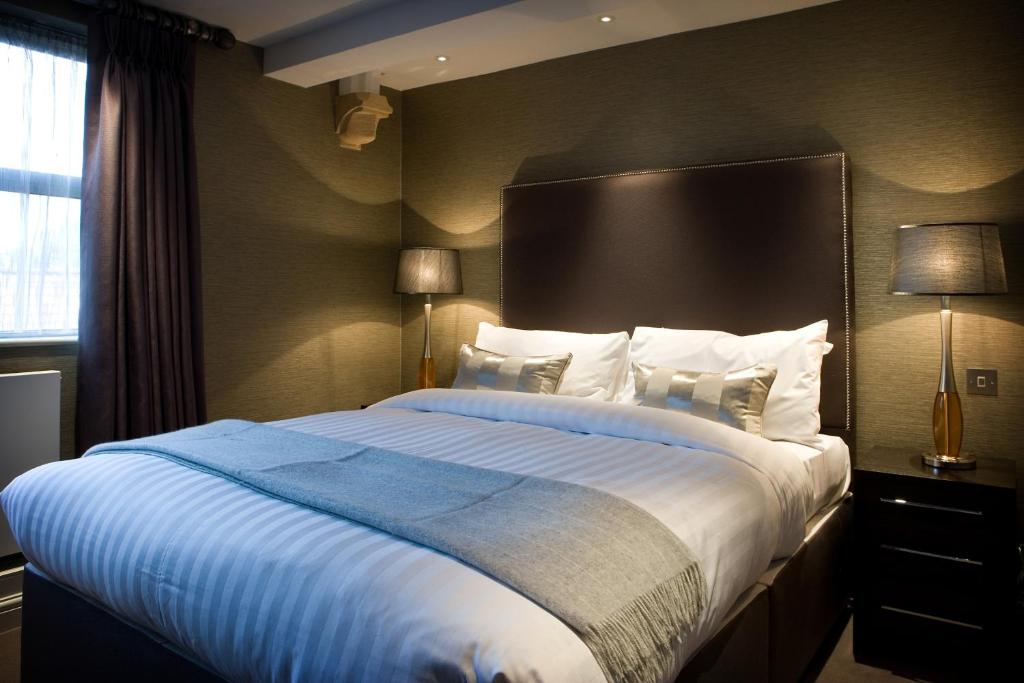 a bedroom with a large bed with a blue blanket at Castle Hotel & Apartments in Lincoln