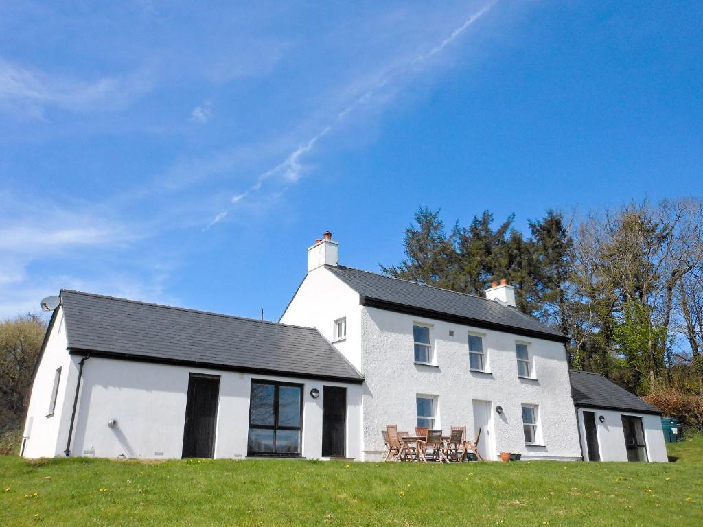 une maison blanche avec une table et des chaises sur un champ dans l'établissement Dolgoed House, à Llangadog