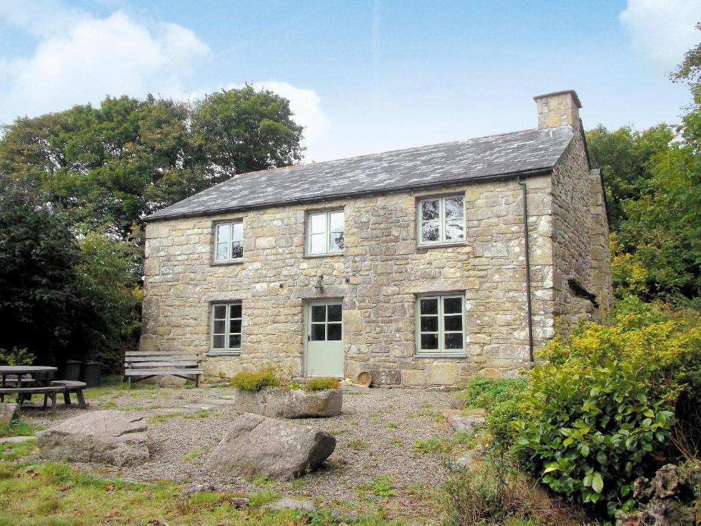 an old stone house with a picnic table and a bench at Higher Thorne Cottage - 28297 in Warleggan