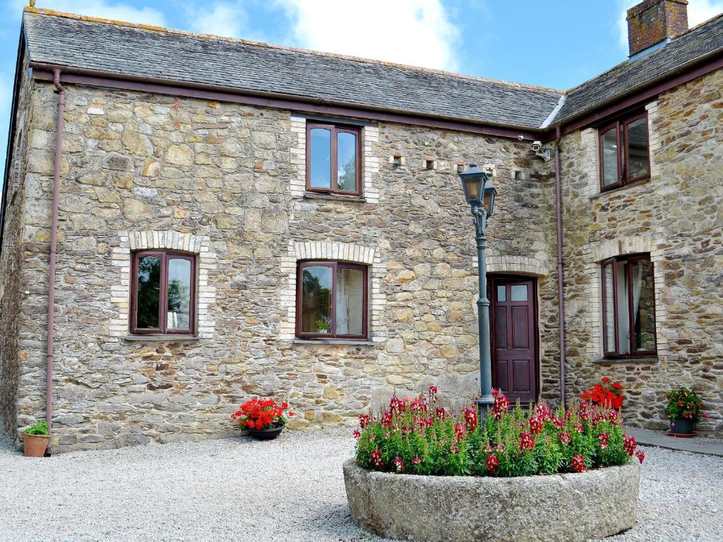 a stone house with flowers in front of it at Anneth Lowen in Pentewan