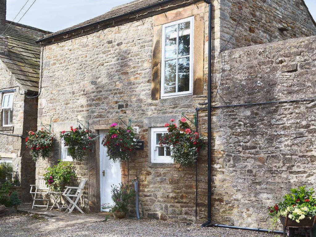 an old brick house with flowers on the door at South View Mews in Romaldkirk