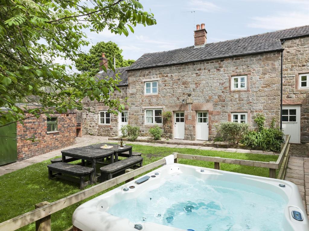 a hot tub in the backyard of a stone house at School House in Leek