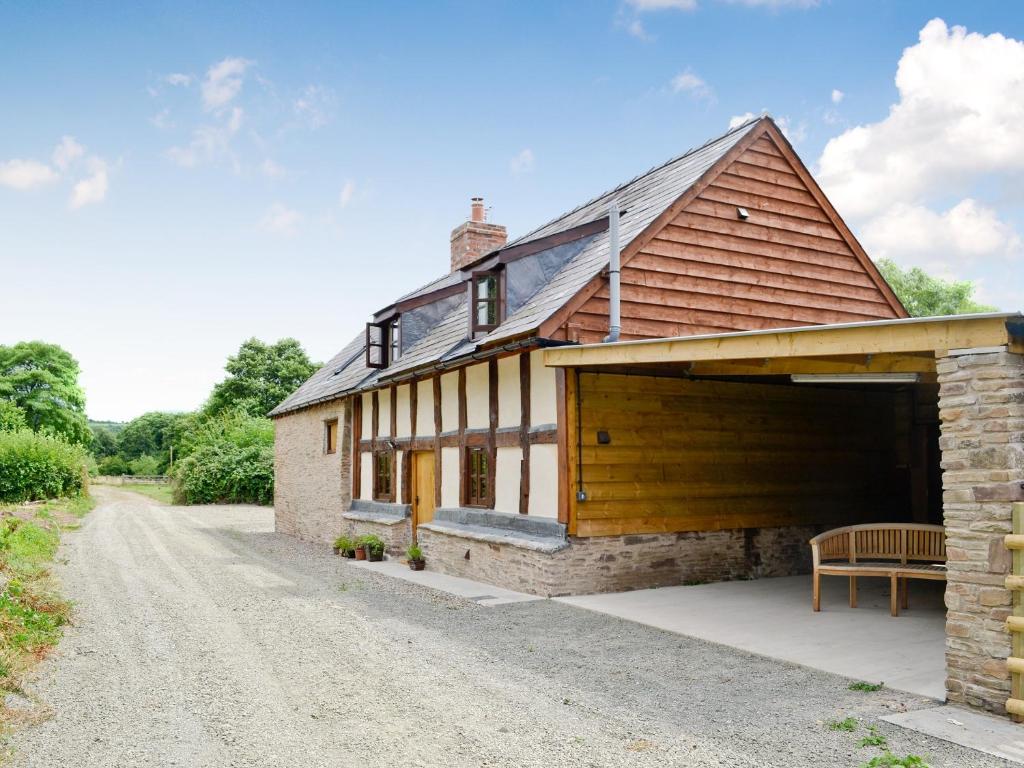 un granero reconvertido con un garaje y un banco en un camino de grava en Mill Cottage, en Peterchurch