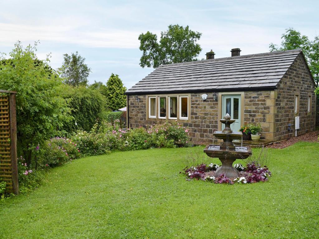 uma pequena casa de pedra com uma fonte no quintal em Thurst House Farm Holiday Cottage em Ripponden