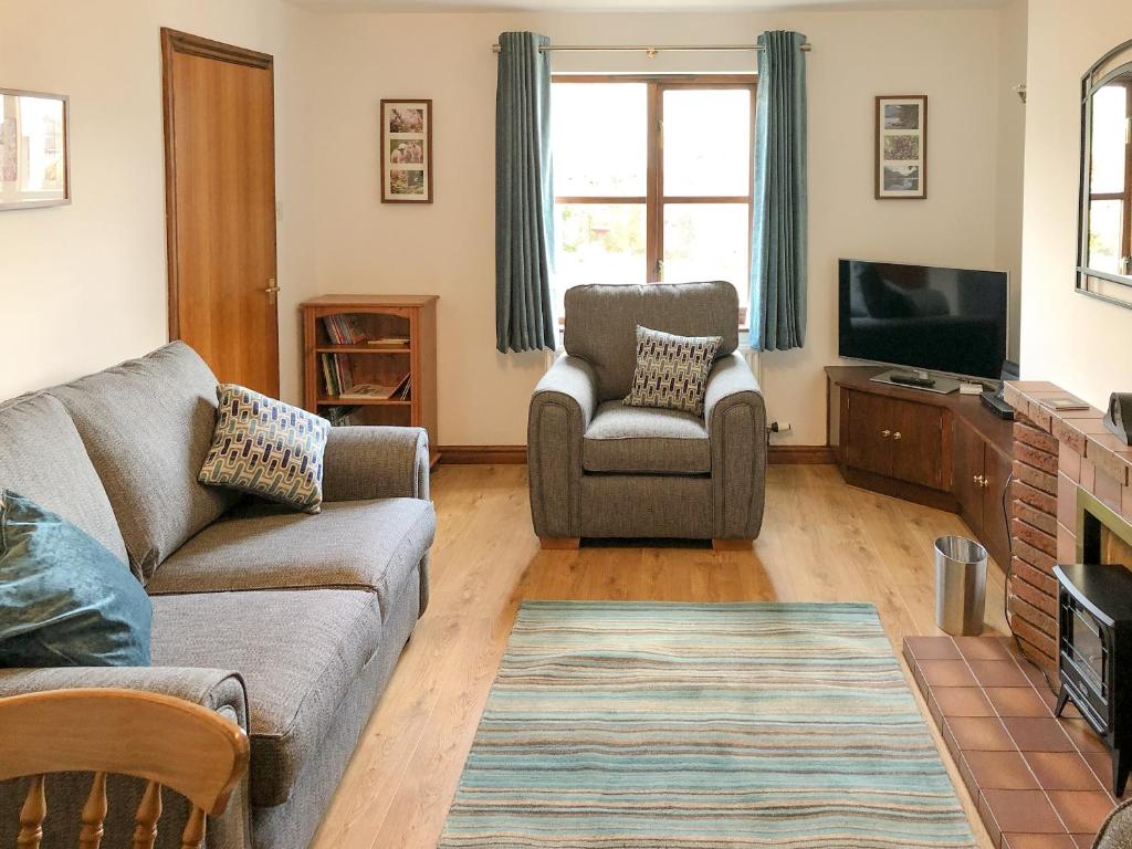 a living room with a couch and a tv at Acorn Cottage in Braithwaite