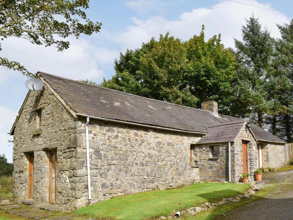 an old stone building with a black roof at Ty Christian in Blaencelyn