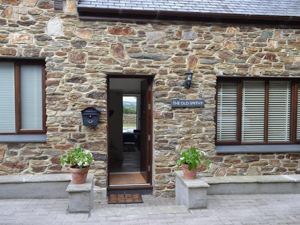 a stone building with a door and two potted plants at The Old Smithy in Kea