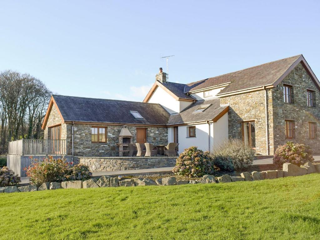 LlanarthにあるThe Farmhouseの緑の芝生の大きな石造りの家