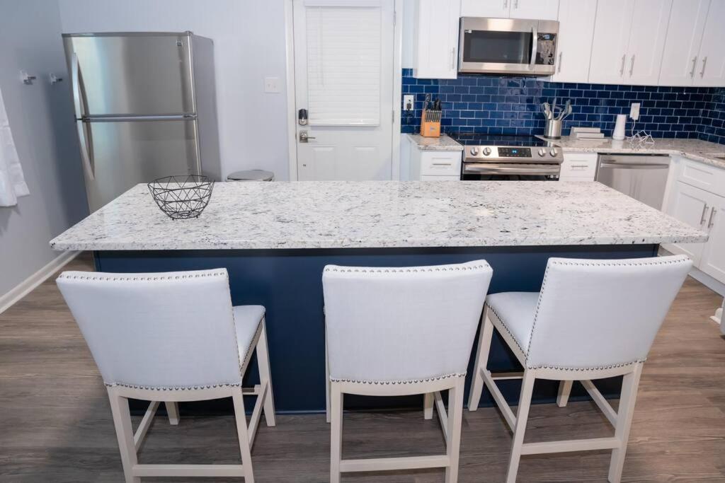 een keuken met een aanrecht met vier witte barkrukken bij Beautiful 3-bedroom home off-street parking. in Greensboro