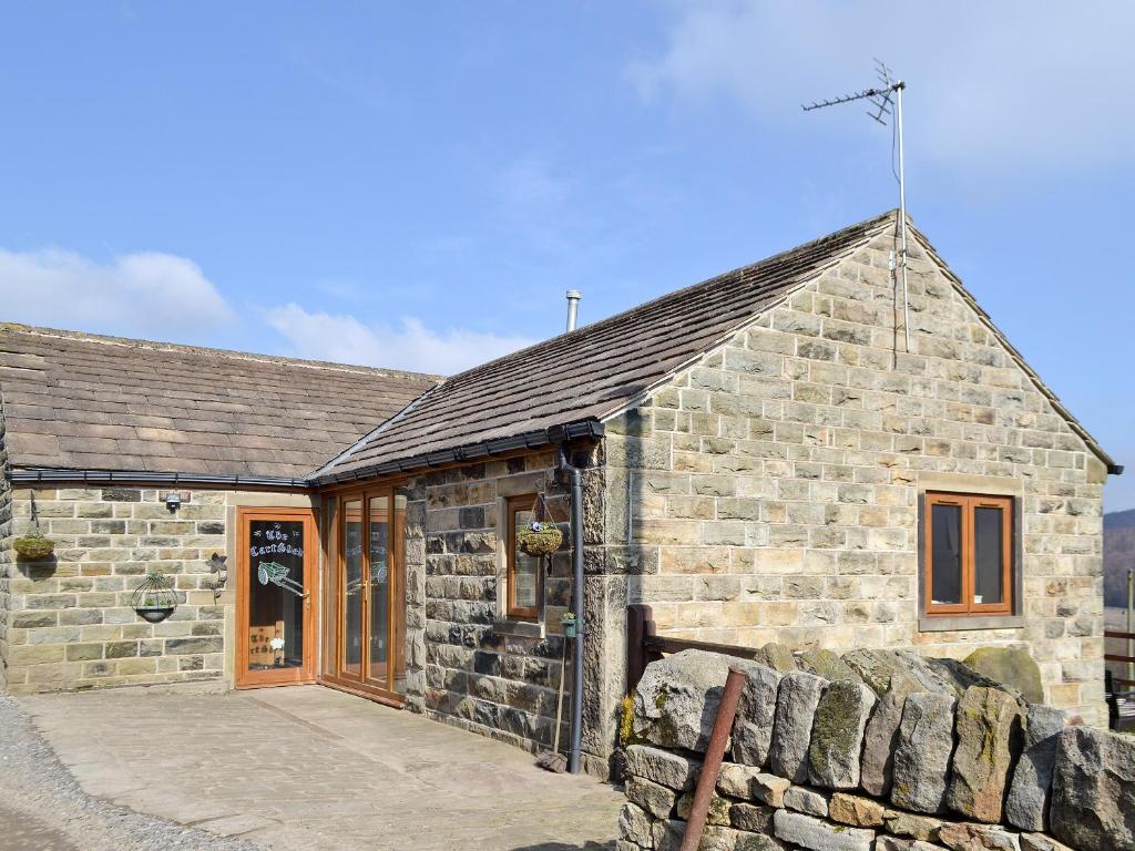 a stone building with a stone wall in front of it at The Cart Shed in Deepcar