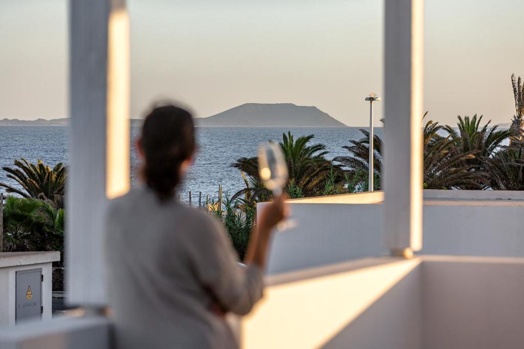 uma mulher olhando para fora de uma janela para o oceano em Sea Moon Lanzarote em Playa Blanca