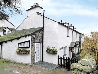 a white house with a black fence and flowers at Rustic Cottage in Bowness-on-Windermere