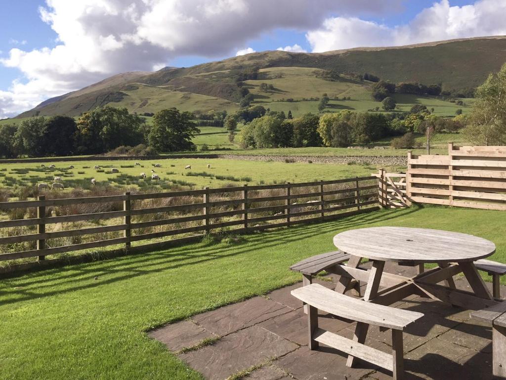 a picnic table and bench in a field with a fence at The Garth in Mungrisdale