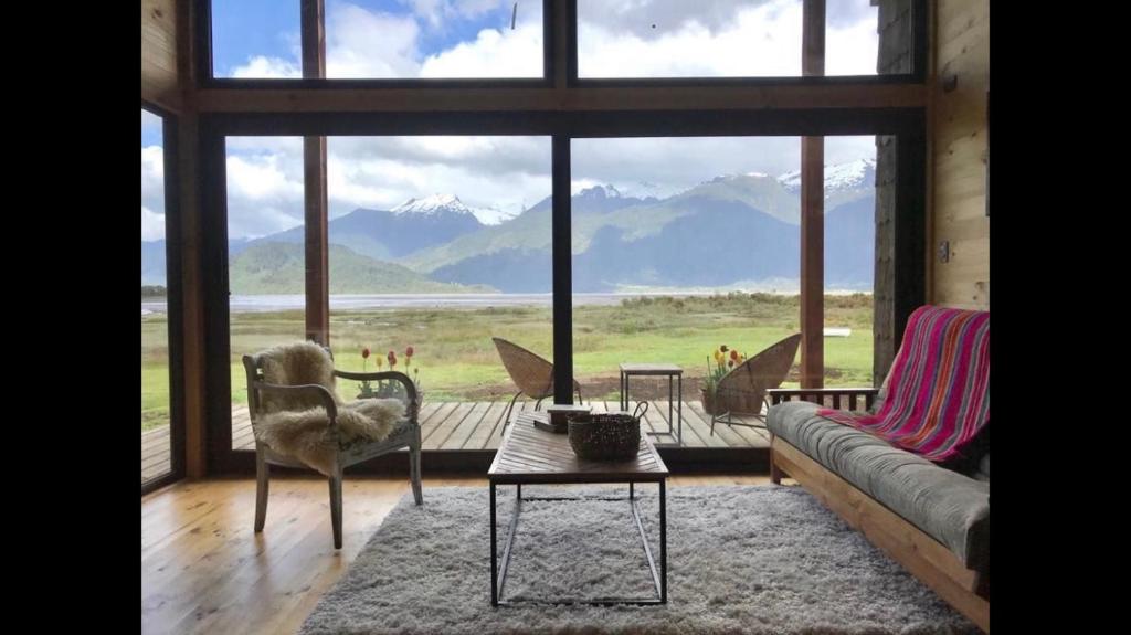 a living room with a couch and a table and a large window at Cabañas Almalik in Ralún