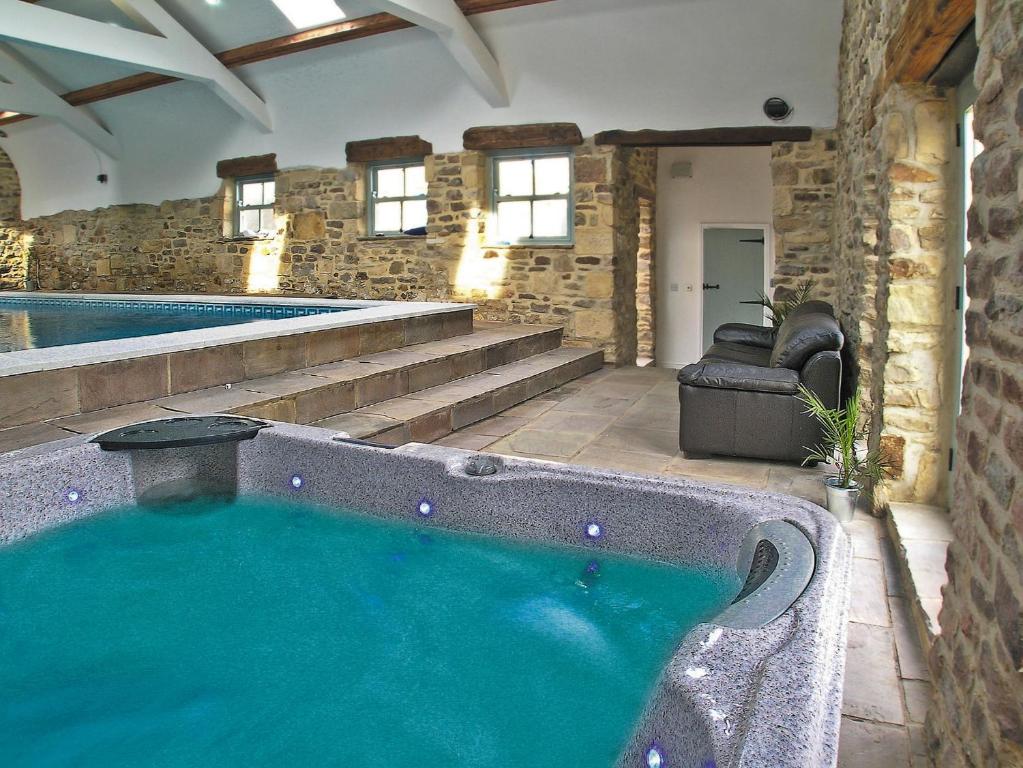 a large swimming pool in a building with a large tub at Raby Cottage-27764 in Wolsingham