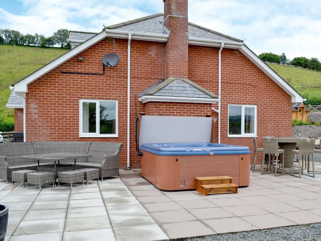 a hot tub on a patio in front of a brick building at Castle View in Llanbadarn-fynydd
