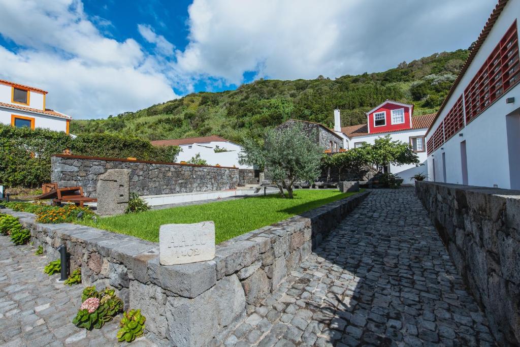 a stone retaining wall next to a street with houses at Casa do Brasão in Lajes do Pico