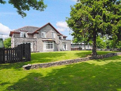 una grande casa in pietra con un albero nel cortile di Silverdale Apartment a Lindale