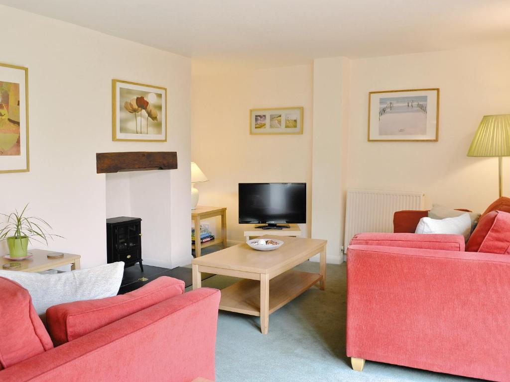 uma sala de estar com dois sofás vermelhos e uma televisão em The Linhay em East Worlington