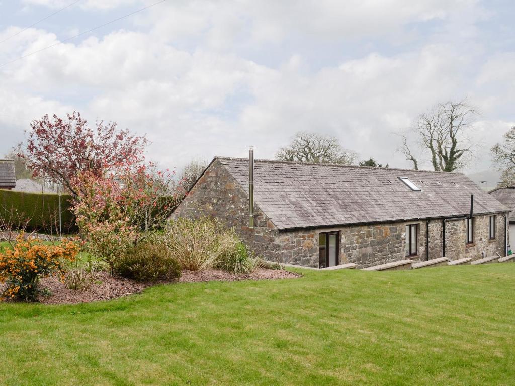 una antigua casa de piedra con un jardín delante de ella en Hameish Holiday Cottage, en Kirkcudbright