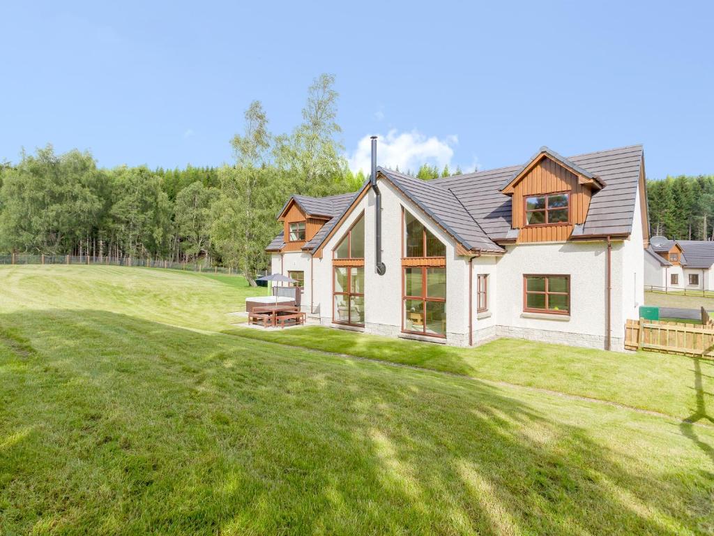 uma casa com um grande quintal com relva em Birch Corner em Aviemore