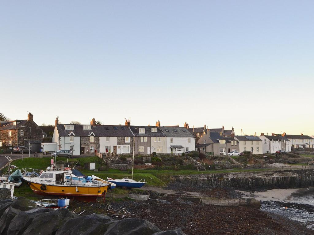two boats are docked in a harbor with houses at Craster View in Craster