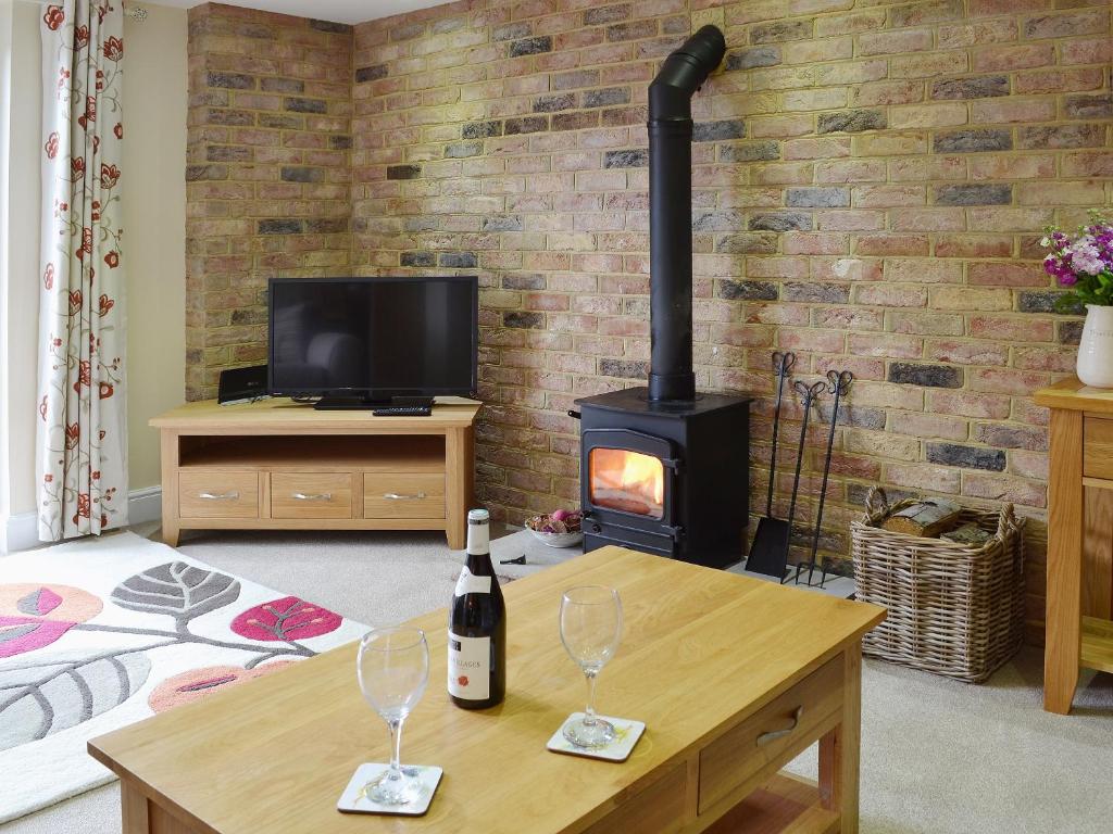 a living room with a wood stove with two wine glasses at Dairy Cottage in Matfield