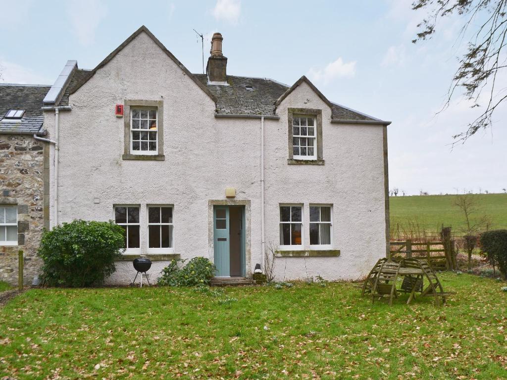 a white brick house with a blue door at Old Inzievar in Blairhall