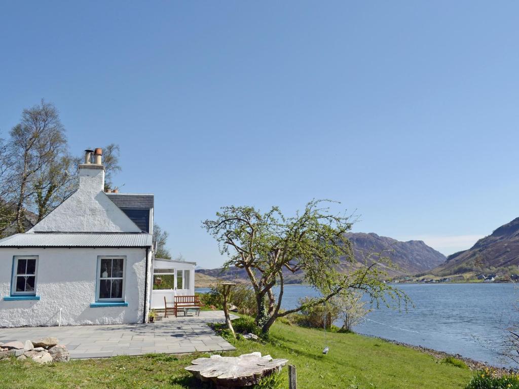 a cottage on the shore of a lake at Loch Shore Cottage in Dornie
