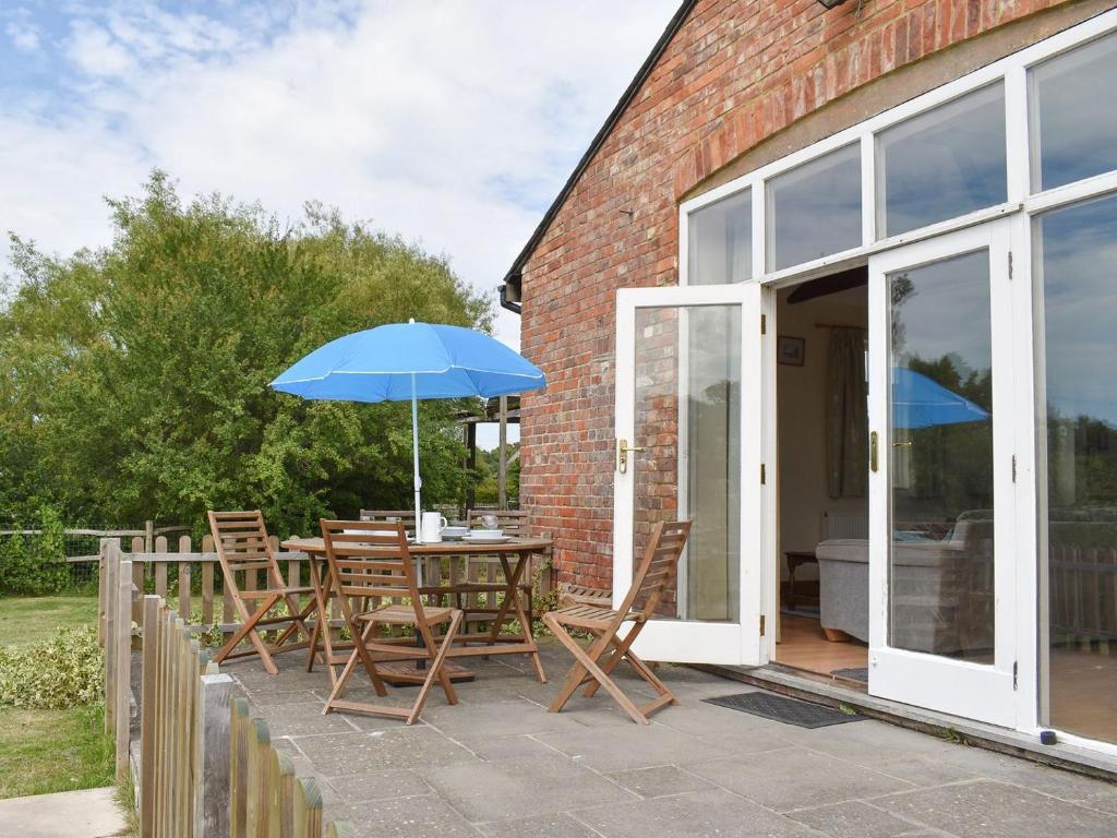 a patio with a table with an umbrella and chairs at The Little Barn in High Halden