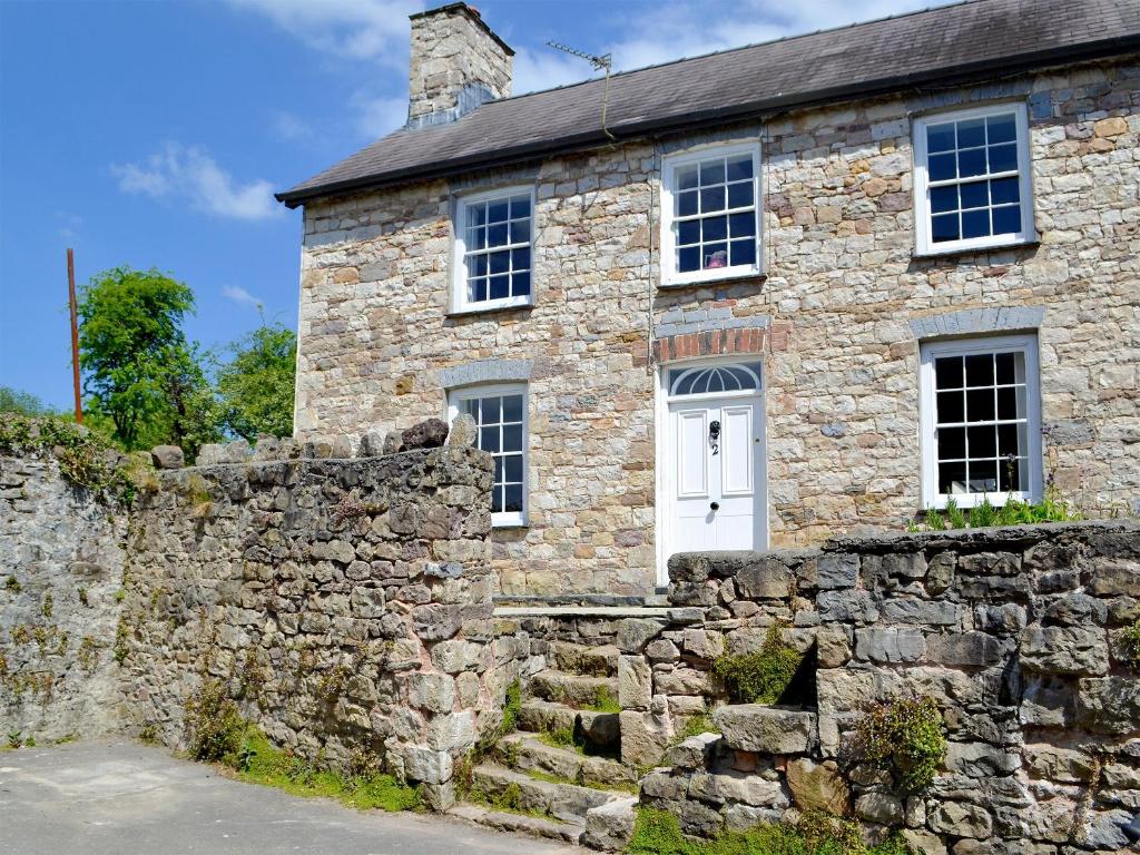 uma antiga casa de pedra com uma parede de pedra em The Mill Farmhouse em Llandybie
