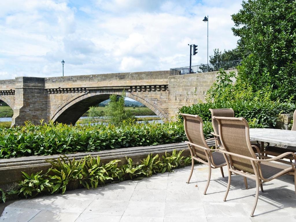 a patio with a table and chairs next to a bridge at The West Wing - 26666 in Corbridge