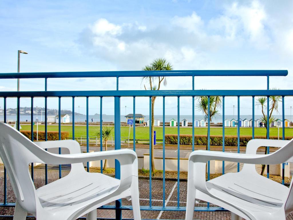 two white chairs sitting on a balcony overlooking the ocean at 15 Belvedere Court in Paignton