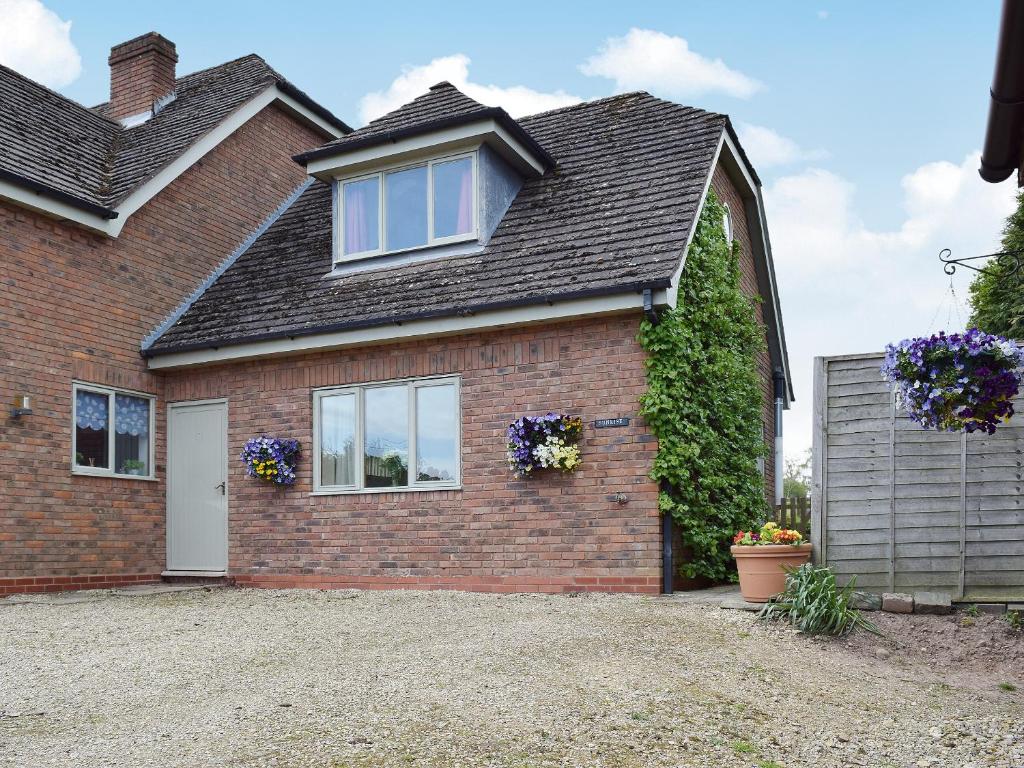 a brick house with a window and flowers on it at Sunrise in Coughton