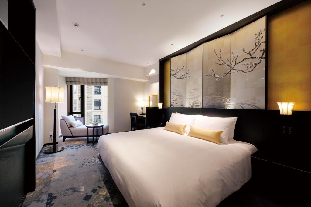 a hotel room with a large white bed and a chair at THE HOTEL SANRAKU KANAZAWA 21th December 2022 OPEN in Kanazawa