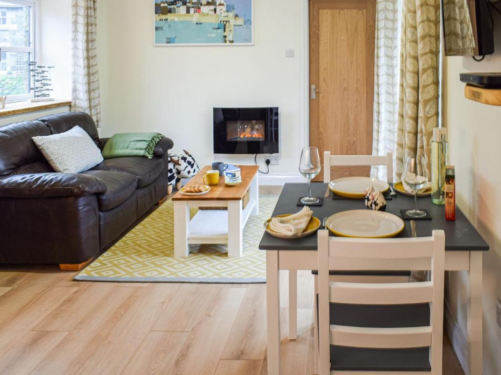 a living room with a table and a couch at Honeysuckle Cottage in Cury