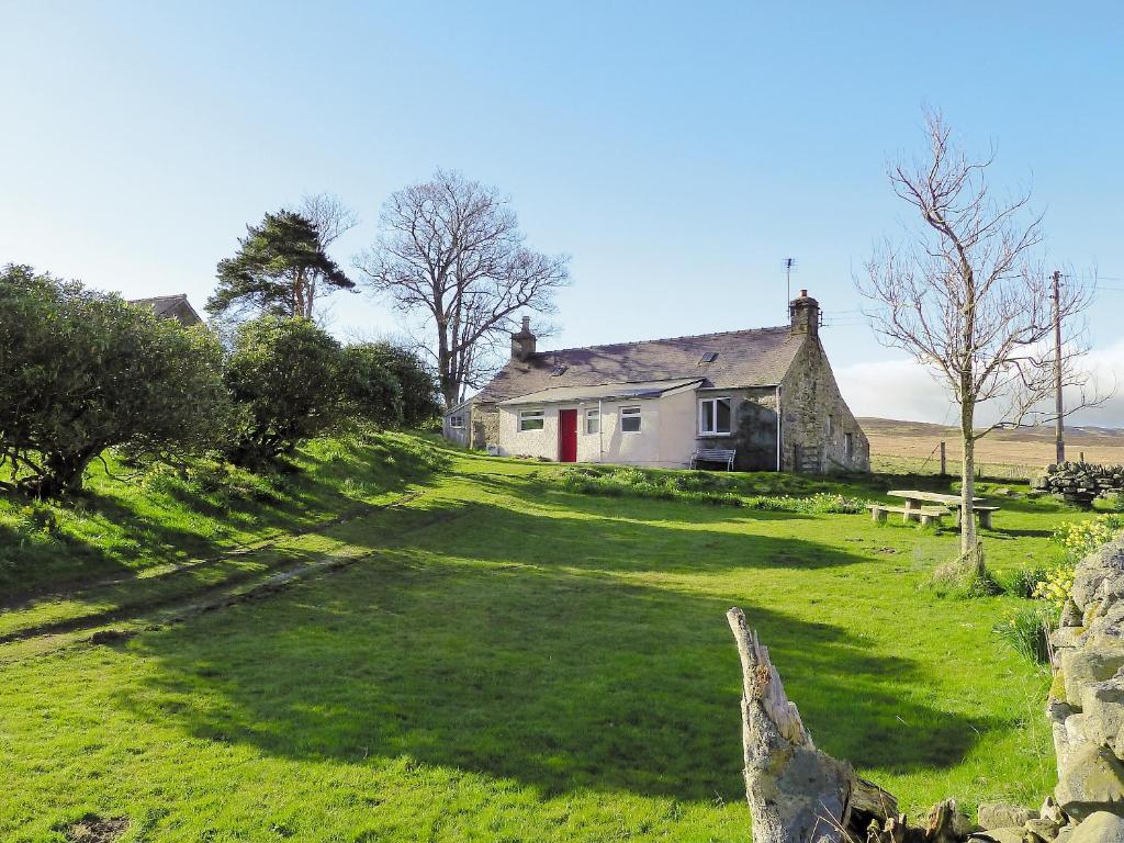una casa en una colina con un patio de césped en Glentairre Cottage - Swww, en Balnaboth