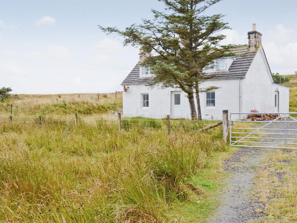 an old white house in a field with a fence at Cor An Easan in Talmine