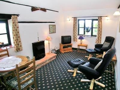 een woonkamer met stoelen en een tafel en een televisie bij Wagtail Barn in Yaxham