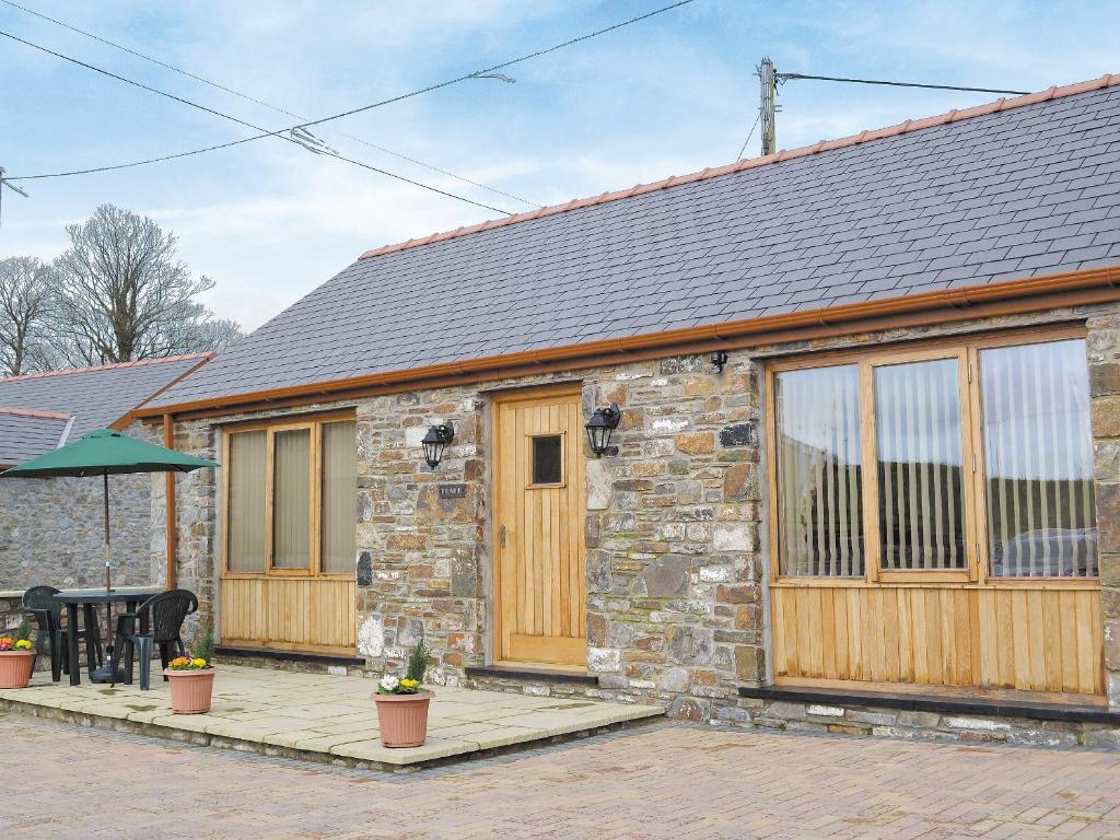 a stone cottage with wooden doors and a patio at The Smithy - Op6 in Carmarthen