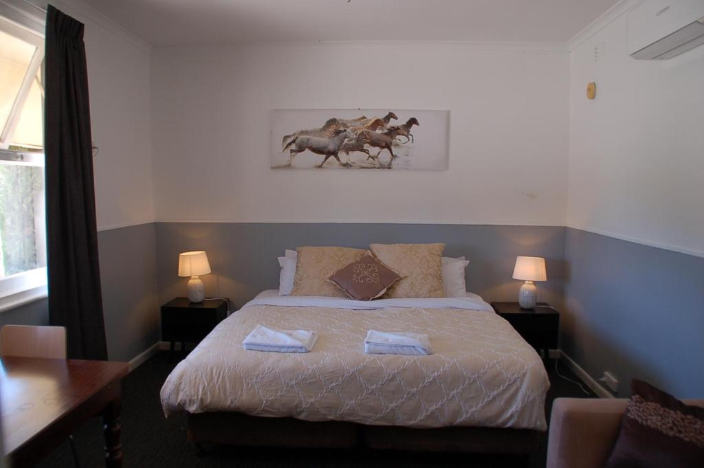 a bedroom with a bed with two horses on it at Calder Motel in Bendigo