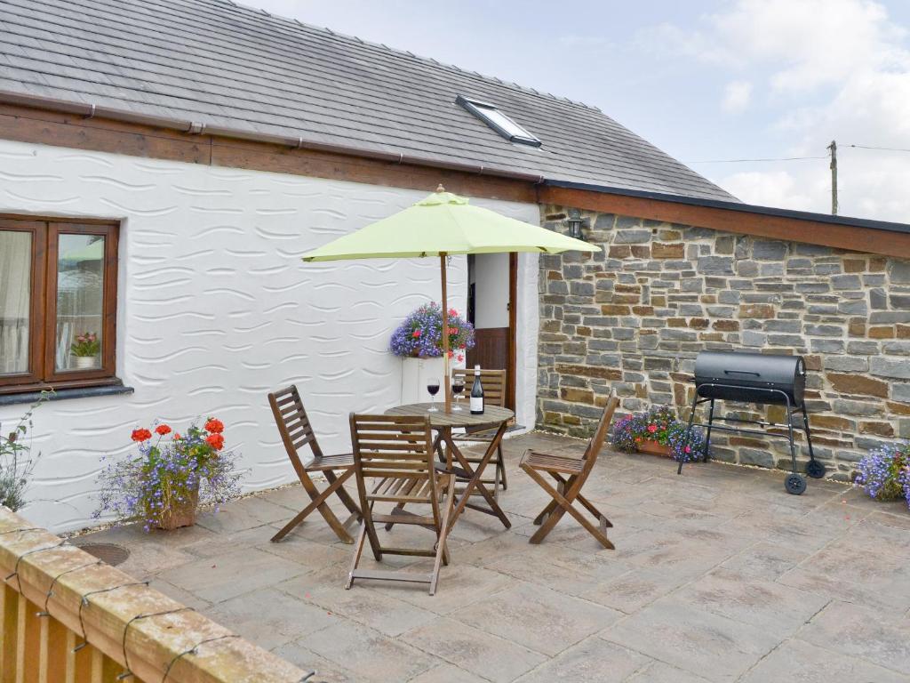 a patio with a table and chairs and an umbrella at Yr Hen Ysgubor - 29176 in Trelech