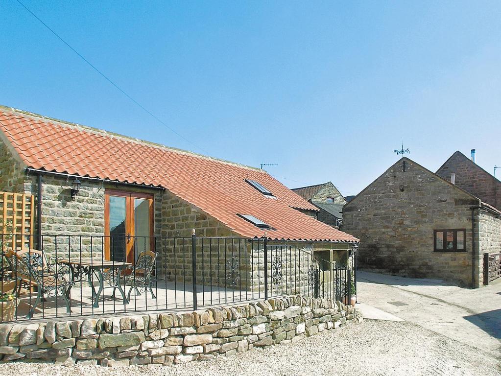 a stone house with a table and a fence at Bramble Cottage-19878 in Cloughton