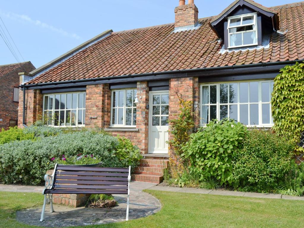 a brick house with a bench in front of it at Jasmine Cottage in Scalby