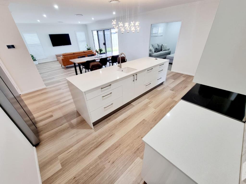 a kitchen with white cabinets and a dining room at Large and Private Executive Home - Secure parking for boats in Hervey Bay