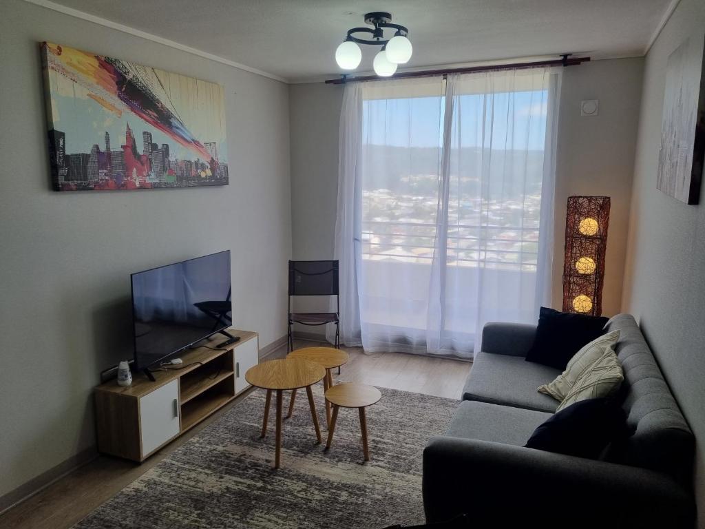 a living room with a couch and a television at Departamento en Tome, Condominio Vista Bahia in Tomé