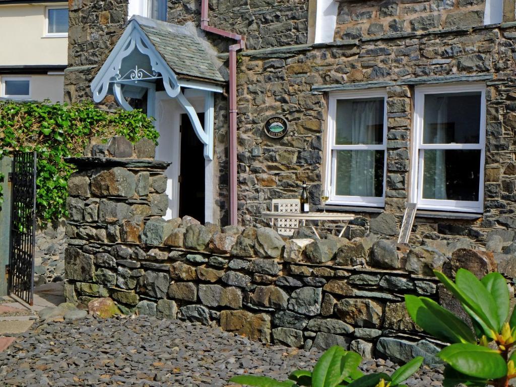 ein Steinhaus mit einem Fenster und einer Steinmauer in der Unterkunft Bunbury Cottage in Keswick